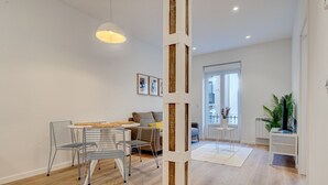 A modern living room with a dining area, a large window, and a view of the city.