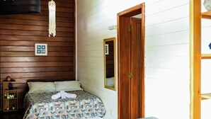 Une chambre à coucher avec un lit, une armoire en bois, un miroir et un panneau lumineux au néon.
