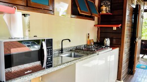 Une cuisine de taille réduite équipée d’un four à micro-ondes, d’un évier et d’une cuisinière.