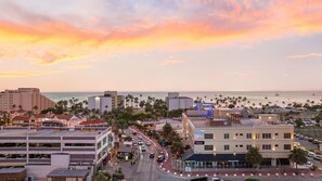 A coastal cityscape with a sunset, featuring a hotel named 'The Cove' with a view of the ocean and palm trees.