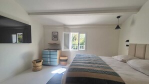 Une chambre à coucher avec un lit, une commode, une fenêtre et un luminaire suspendu.