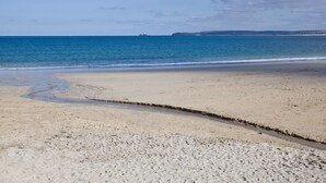 A beach with a sandy shore and calm sea.
