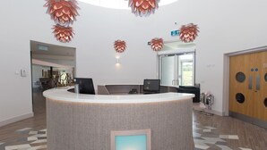 A reception desk with a woven texture, a digital screen, and a patterned floor.