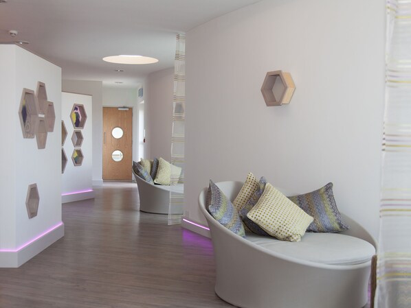 A modern interior with a curved seating area, wooden wall art, and a wooden door with circular windows.