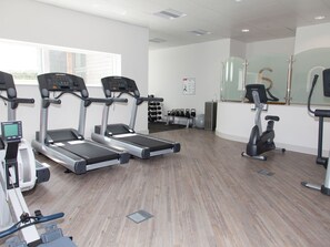 Un gimnasio con cintas de correr, elípticas y una máquina de remo.