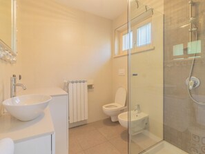 A bathroom with a glass-enclosed shower, a white sink, and a toilet.