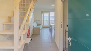 A staircase leading to a balcony, a white sofa, a table, and a teal door.
