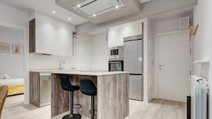 A modern kitchen with a central island, bar stools, and a built-in oven.