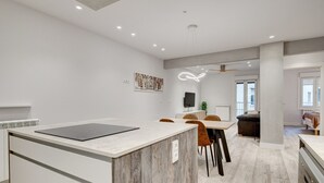A modern kitchen with a marble countertop, a dining area with chairs, and a ceiling fan.