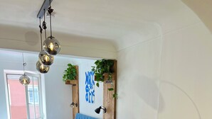Une chambre à coucher moderne avec un lit, un canapé gris, une tête de lit bleue et un mur en bois orné de plantes.