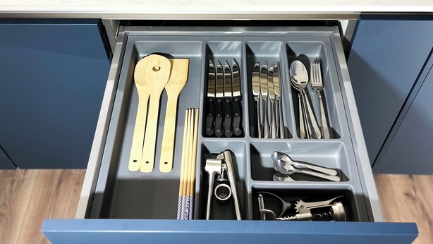 Une cuisine équipée d’une plaque de cuisson à induction intégrée et d’un tiroir avec des compartiments pour ranger les ustensiles et les accessoires de cuisine.