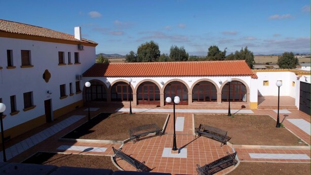 A courtyard with a white building featuring arched doorways and a red-tiled roof. - Turismo rural Valsequillo (Valsequillo)