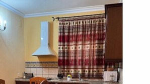 A kitchen with a dining table, chairs, a stove, and a microwave. - Turismo rural Valsequillo (Valsequillo)