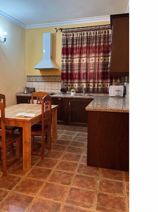 Una cocina con mesa, sillas, estufa y microondas.