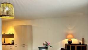 A dining area with a round table, chairs, a vase of flowers, and a lamp. - Villa Laurier U Benedettu (Lecci)