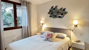 A bedroom with a large bed, two bedside tables, a wall-mounted fish decoration, and a window with curtains. - Villa Laurier U Benedettu (Lecci)