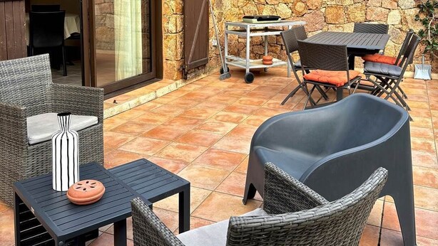An outdoor patio with wicker furniture, a stone wall, and a tiled floor. - Villa Laurier U Benedettu (Lecci)