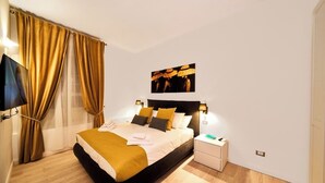 A modern bedroom with a black bed frame, a white nightstand, and a wall-mounted TV. - "Vatican Meadows," with its lovely "Red" apartment. (Roma)