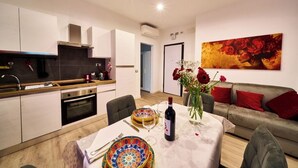 A modern kitchen with white cabinets, a wooden countertop, and a dining area with a table set for two. - "Vatican Meadows," with its lovely "Red" apartment. (Roma)