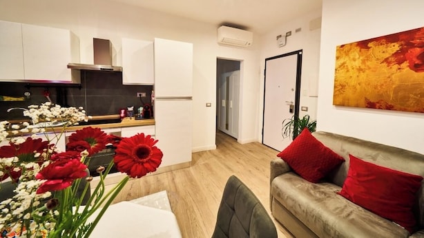 A modern kitchen with white cabinets, a stainless steel range hood, and a dining area with a table and chairs. - "Vatican Meadows," with its lovely "Red" apartment. (Roma)