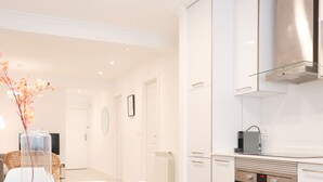 A modern kitchen with white cabinetry, a stainless steel range hood, and a built-in oven.