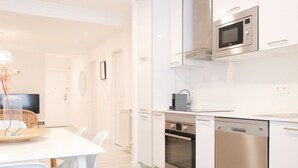 A modern kitchen with white cabinetry, a built-in microwave, oven, and dishwasher.