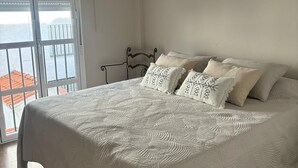 Ein Schlafzimmer mit einem großen Bett, Meerblick durch ein Fenster und einer Klimaanlage an der Wand.