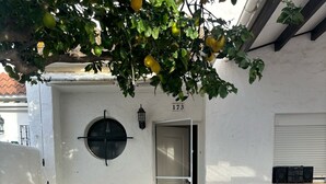 Eine Terrasse mit künstlichem Rasen, einer weißen Tür, einem kleinen Tisch mit Stühlen und einer Lautsprecheranlage.