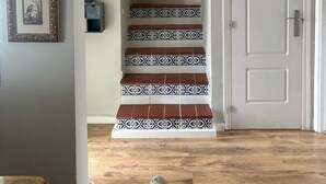 Eine Treppe mit gemusterten Fliesen, eine weiße Tür und ein gerahmtes Bild an der Wand.