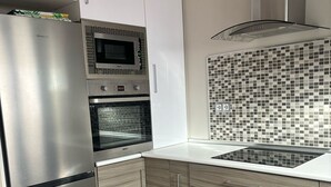 Eine moderne Küche mit Edelstahlgeräten, einer Mikrowelle, einem Backofen und einer gefliesten Rückwand.
