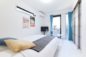 A hotel room with a bed, a TV, a small table with chairs, and a balcony with curtains. - Flora Maison Kamiochiai by Tranova (Tokyo)