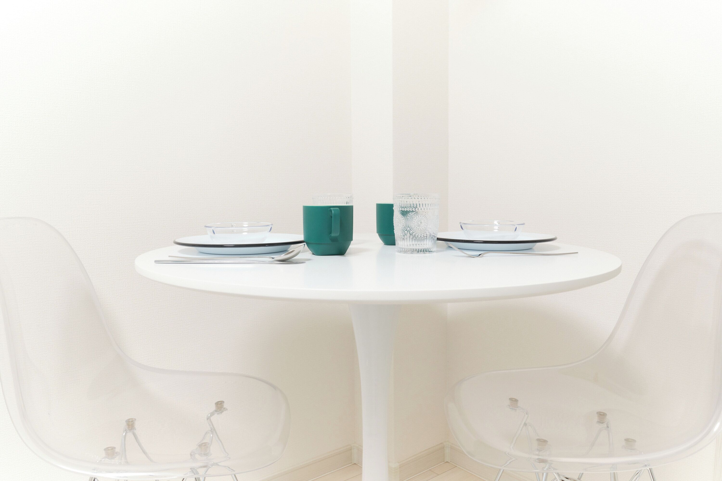 A round white table with two chairs, each with a clear glass base.