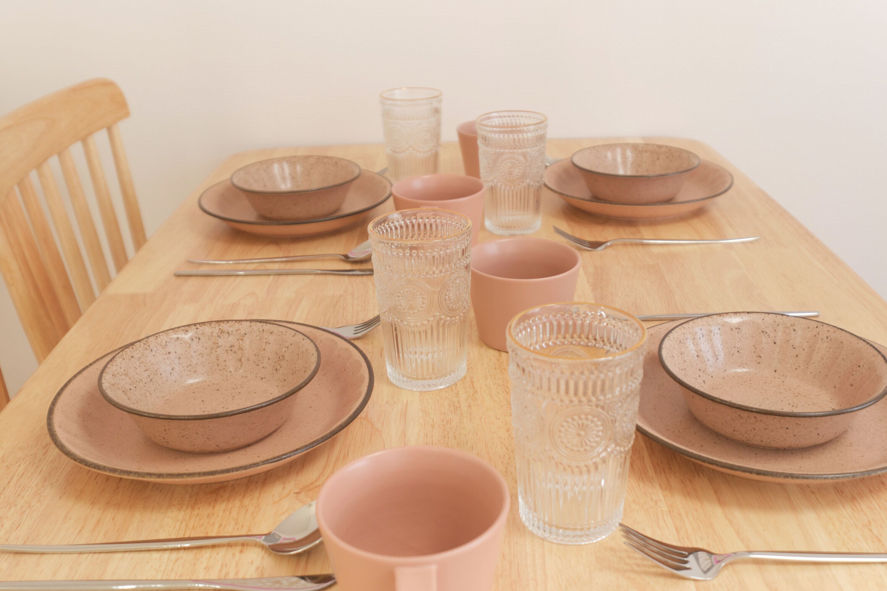 A dining table set with plates, bowls, glasses, and cutlery.