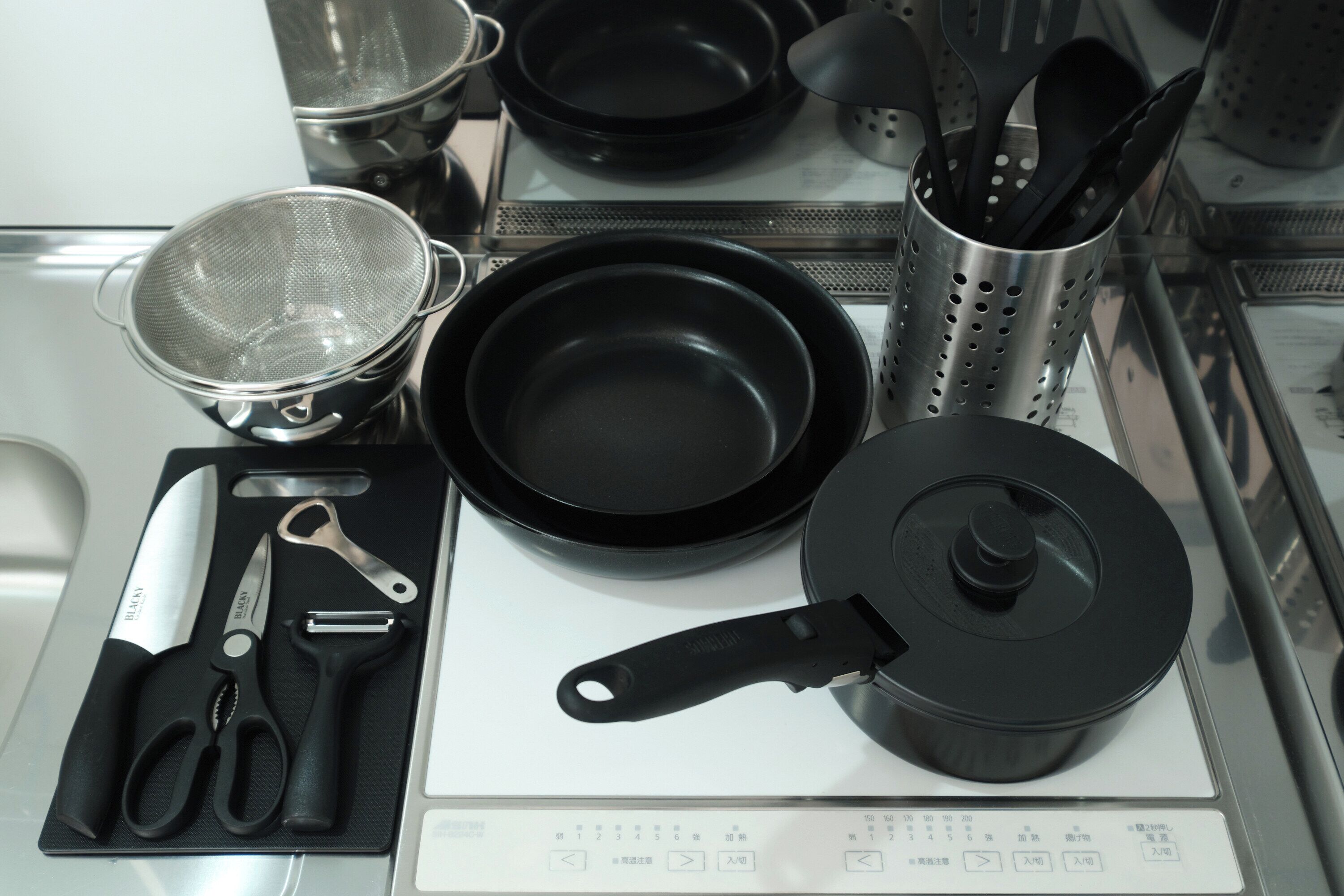 A kitchen with a stove, pots, pans, and utensils.