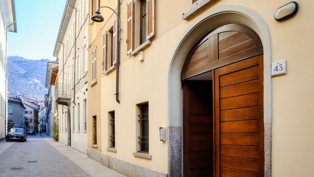 Eine schmale Straße mit einem Gebäude, das eine große Holztür und ein Schild mit der Nummer 43 hat.
