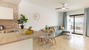 A modern kitchen with a dining area, a sofa, and a view of the outdoors.