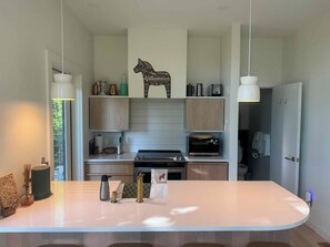 A modern kitchen with a central island, wooden cabinets, and a decorative wall piece.
