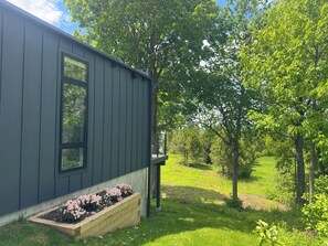A modern building with a dark exterior, a wooden deck, and a flower bed.