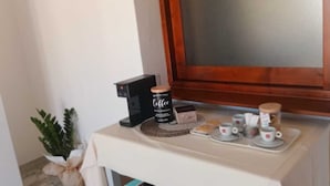 A small table with a coffee maker, a jar of coffee, and a tray with cups and saucers.