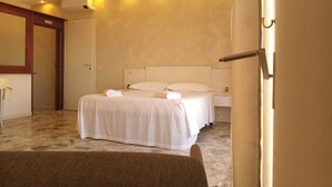 A hotel room with a large bed, a bedside table, and a wardrobe.