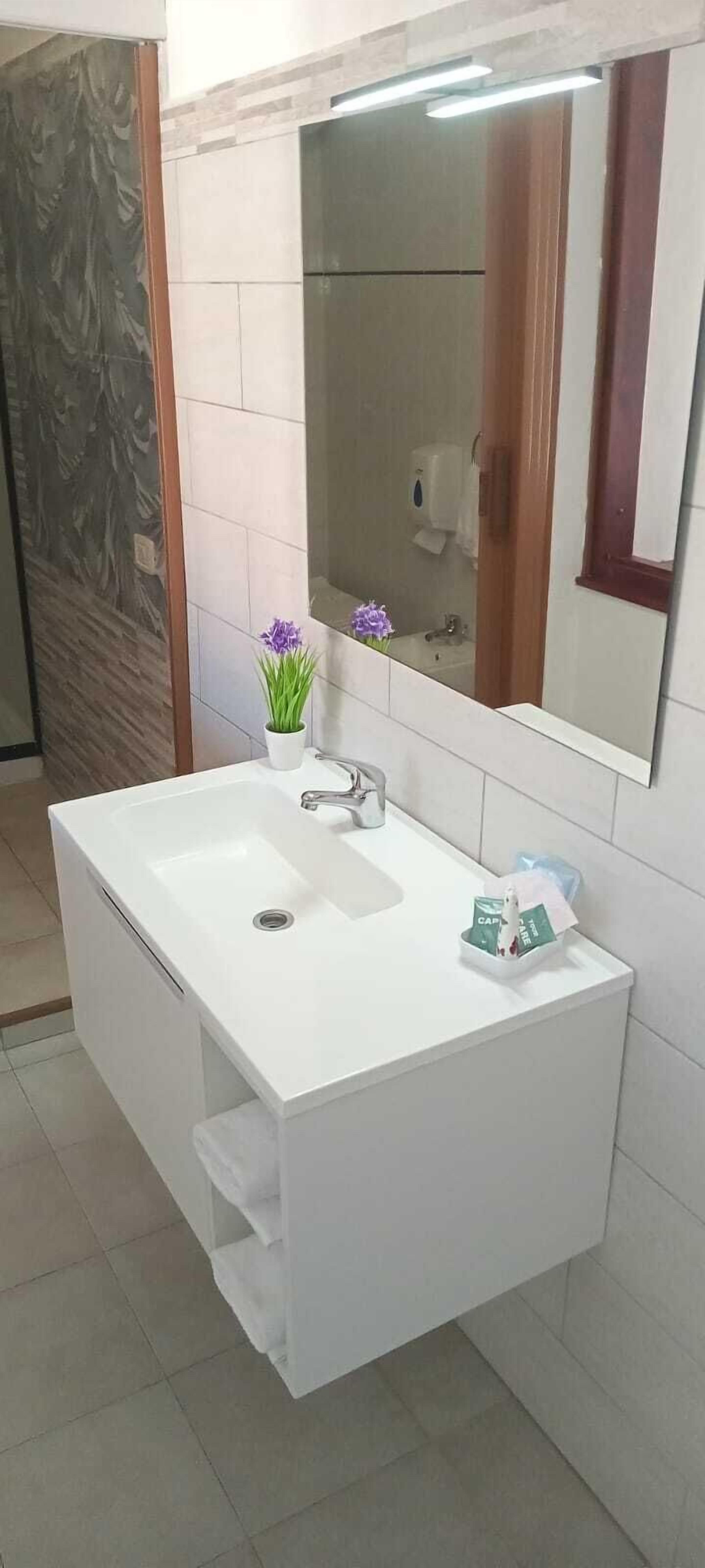 A bathroom with a white vanity, a mirror, and a sink.