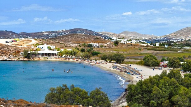 Une ville côtière dotée d’une plage, d’eaux d’un bleu limpide et d’un bâtiment blanc avec un balcon donnant sur la mer.