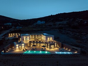 A modern villa with a swimming pool, outdoor seating, and a stone facade. - Aegean Hestia Luxury Villa of Paros (Paros)