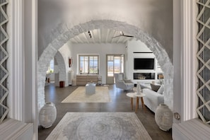 Amplia sala de estar con un arco blanco, una chimenea, un sofá y un televisor.