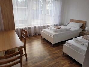 A bedroom with a wooden floor, a bed with white bedding, a wooden nightstand, and a chair. - Horrem City Apartments (Kerpen)