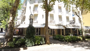 Un hotel de varios pisos con balcones, un letrero de póker y un jardín bien cuidado.