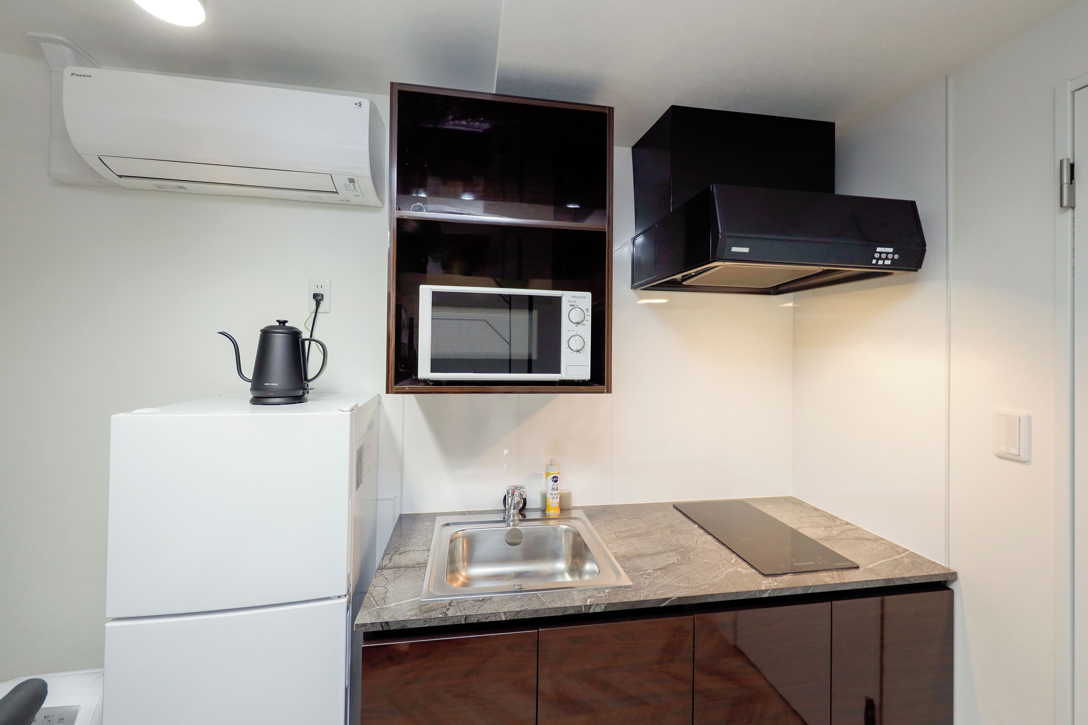A compact kitchen with a built-in microwave, a coffee maker, and a sink.