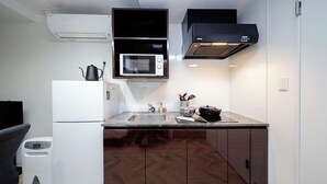 Una cucina compatta con forno a microonde, piano cottura e frigorifero.