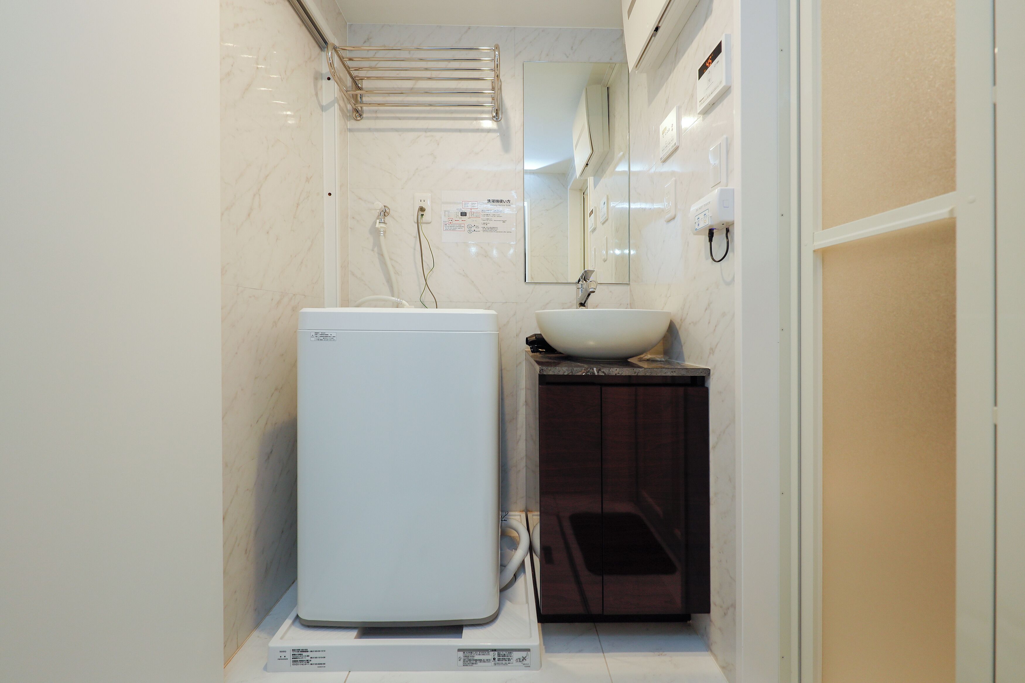 A compact bathroom with a white refrigerator, a sink, and a dark cabinet.
