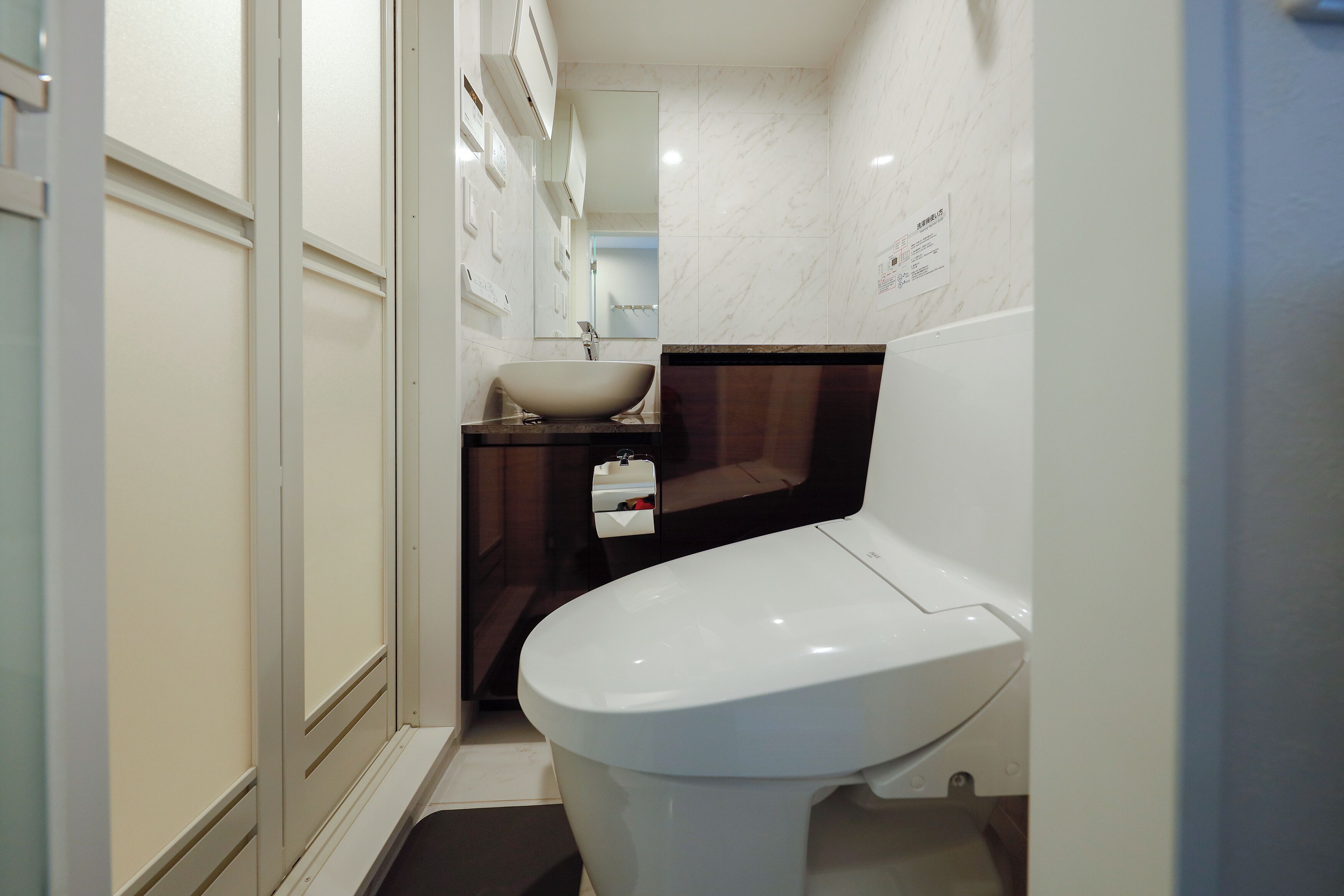 Une petite salle de bain avec des toilettes blanches, un lavabo et un miroir.